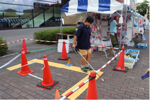 ブラインド状態で白杖を持って歩行体験をしている様子